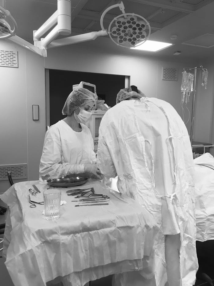 Healthcare professionals in an operating room performing surgery with tools and equipment.
